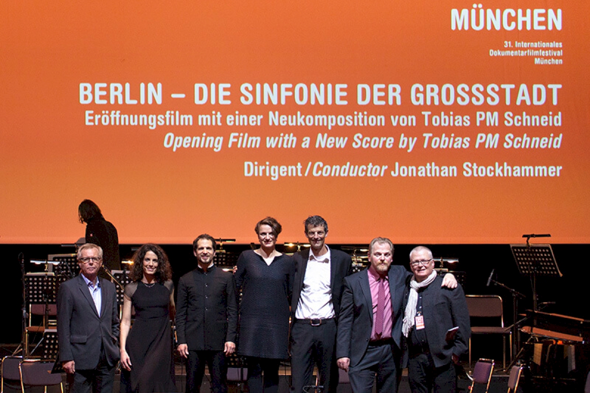 v.l.n.r. Helmut Späth (Vorstand Versicherungskammer Kulturstiftung), Maya Reichert (Moderation), Jonathan Stockhammer (Dirigent), Barbara Soldner (Geschäftsführung Versicherungskammer Kulturstiftung), Daniel Sponsel (Leiter DOK.fest), Tobias PM Schneid (Komponist), Florian Ganslmeier (Geschäftsführer Münchener Kammerorchester) © DOK.fest