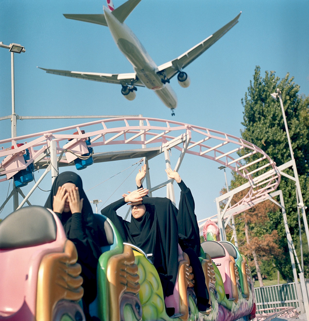A plane flies low over students riding a train at a funfair over the weekend, Istanbul, Turkey, August 29, 2018. © Sabiha Çimen/Magnum Photos